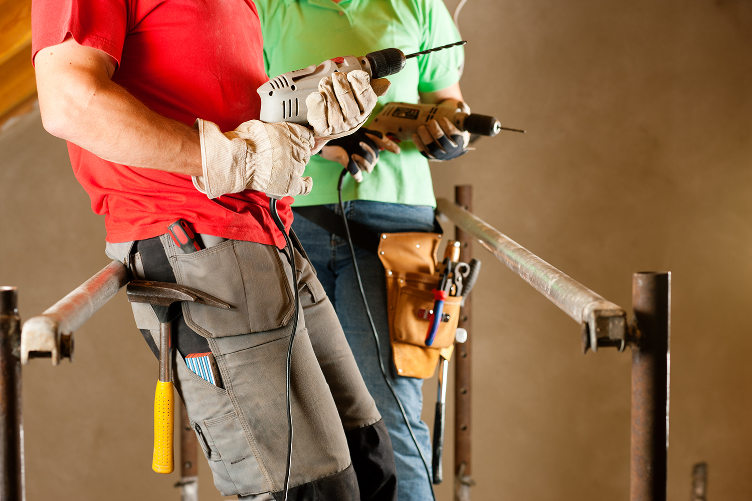 DIY couple in home improvement with hand drill standing on a scaffold